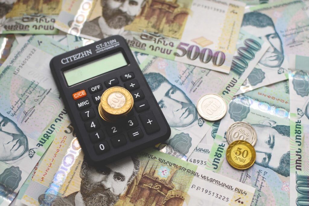 FXの証拠金に対する安全な損失額を計算するために、紙幣の上に置かれた電卓と積まれたコイン。