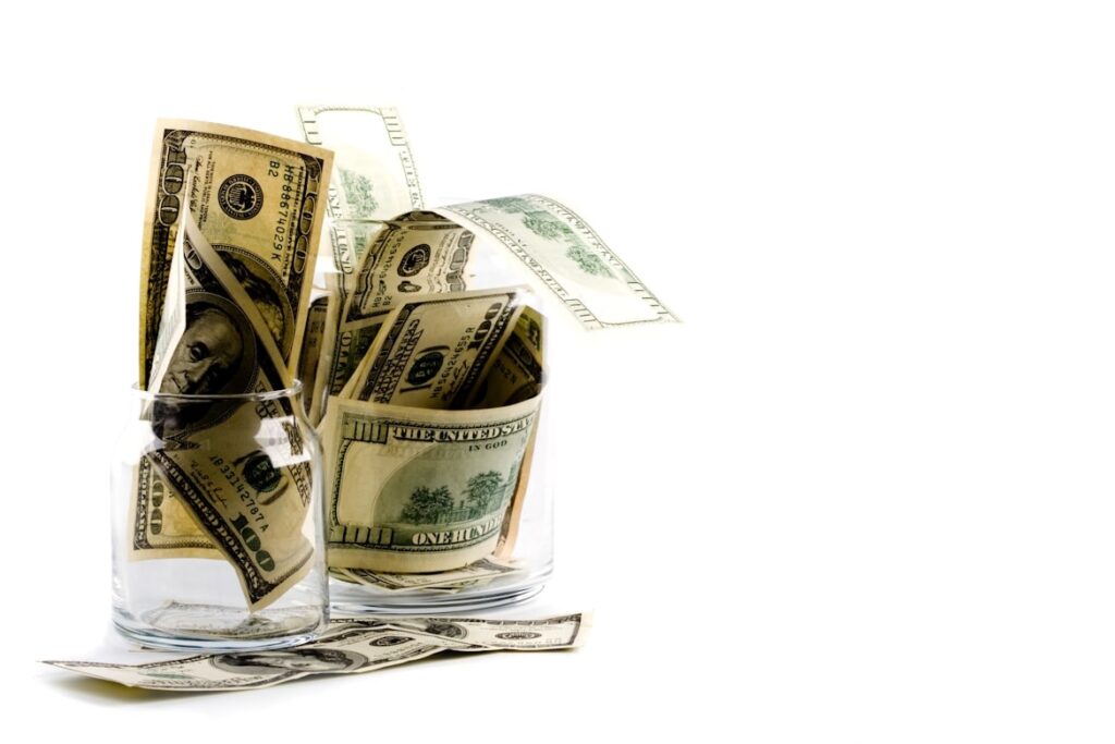 FXの証拠金として運用する余剰資金を、生活費と分けて管理するイメージ。ガラス瓶に入ったドル紙幣。